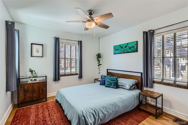 bedroom with ceiling fan, visible vents, baseboards, and wood finished floors