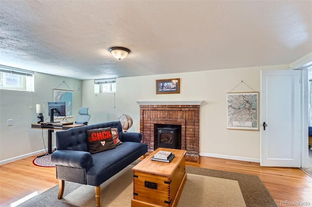 living area featuring wood finished floors, a healthy amount of sunlight, baseboards, and a textured ceiling