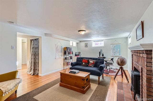 living room featuring light wood-style floors, baseboards, and a textured ceiling