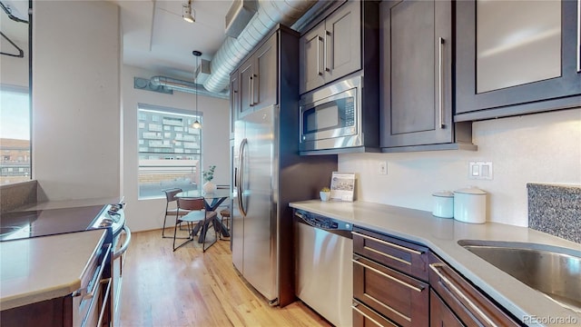 kitchen featuring dark brown cabinets, stainless steel appliances, and hanging light fixtures