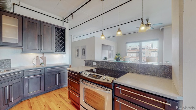 kitchen featuring ceiling fan, backsplash, stainless steel electric range, dark brown cabinets, and light wood-type flooring