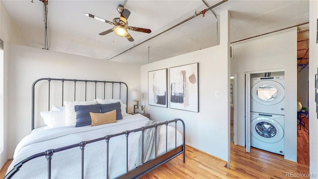 bedroom with ceiling fan, stacked washer and dryer, and hardwood / wood-style flooring