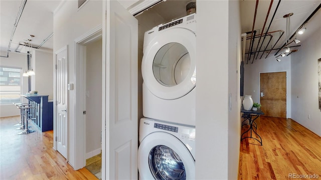 clothes washing area featuring light hardwood / wood-style flooring and stacked washer / dryer