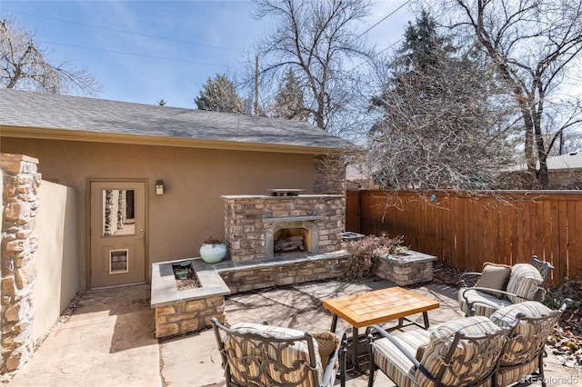 view of patio / terrace with an outdoor stone fireplace and fence