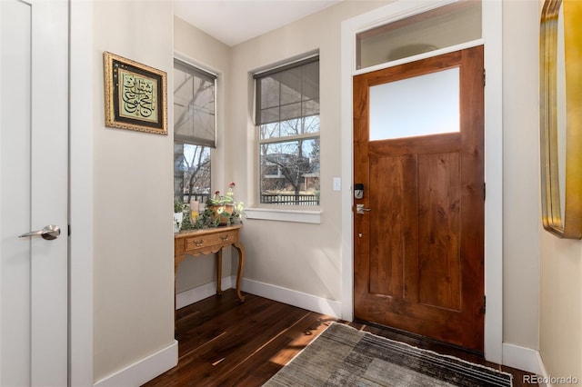 foyer entrance with dark wood-style floors and baseboards