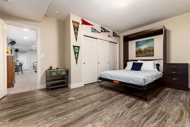 bedroom with wood finished floors, a closet, and baseboards