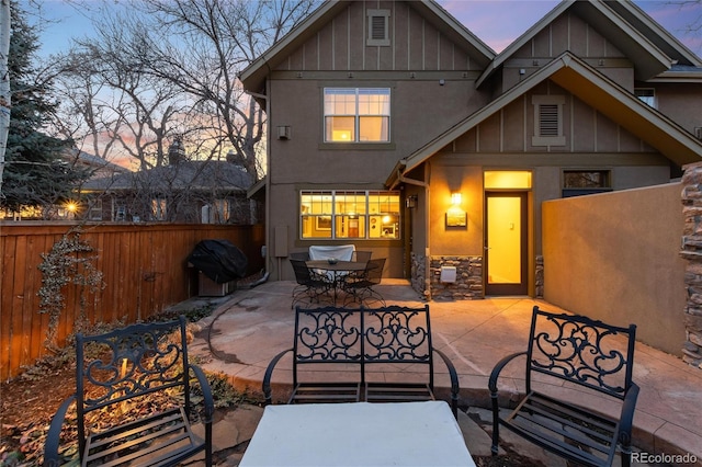 patio terrace at dusk featuring area for grilling and fence