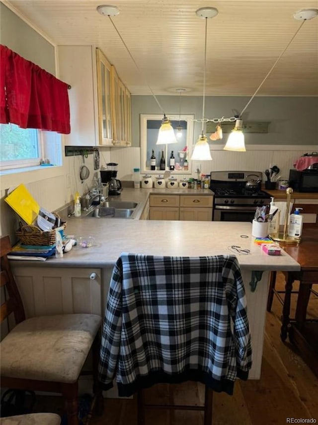 kitchen with decorative light fixtures, sink, a kitchen breakfast bar, kitchen peninsula, and gas range