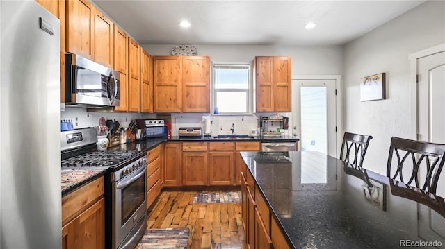 1086 Johnson St, Wiggins, CO 80654 - kitchen with appliances with stainless steel finishes, wood-type flooring, recessed lighting, dark stone counters, and a sink