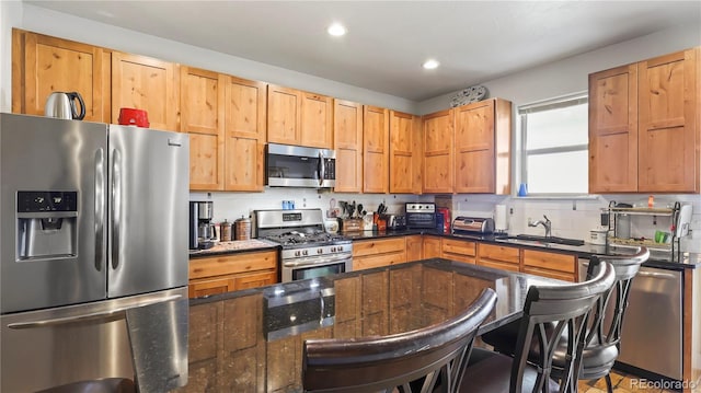 1086 Johnson St, Wiggins, CO 80654 - kitchen with appliances with stainless steel finishes, a sink, a breakfast bar, recessed lighting, and dark stone counters