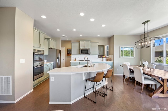 20855 Park Hollow Dr, Parker, CO 80138 - kitchen featuring appliances with stainless steel finishes, a center island with sink, a sink, baseboards, and dark wood-type flooring