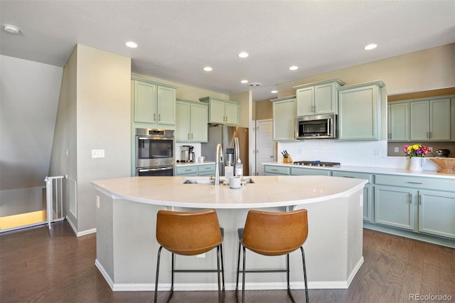 20855 Park Hollow Dr, Parker, CO 80138 - kitchen with appliances with stainless steel finishes, an island with sink, dark wood-type flooring, a breakfast bar area, and recessed lighting