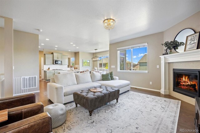 20855 Park Hollow Dr, Parker, CO 80138 - living room with wood finished floors, a glass covered fireplace, recessed lighting, baseboards, and a chandelier