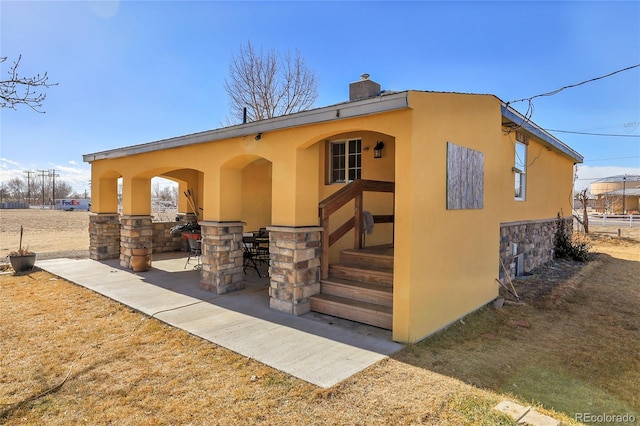 724 County Road 37, Brighton, CO 80603 - back of house featuring a patio area, a chimney, stucco siding, and stone siding