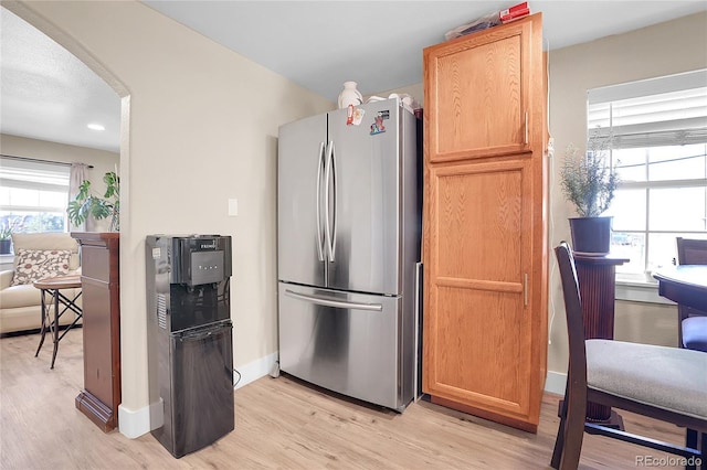 724 County Road 37, Brighton, CO 80603 - kitchen featuring baseboards, arched walkways, light wood-style floors, and freestanding refrigerator