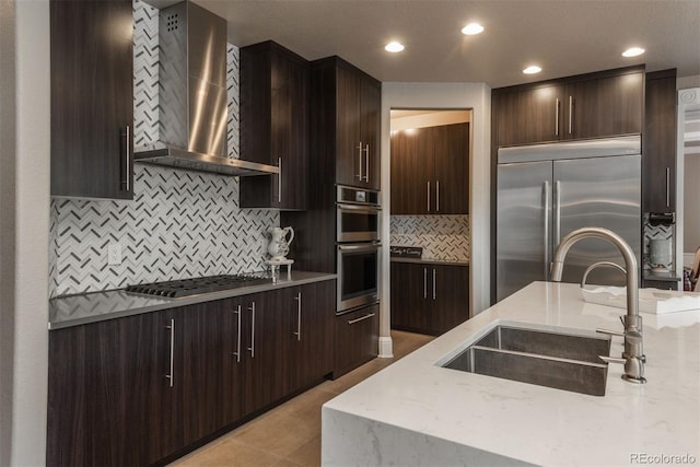 171 October Pl, Castle Rock, CO 80104 - kitchen with wall chimney exhaust hood, appliances with stainless steel finishes, backsplash, light stone countertops, and dark brown cabinets