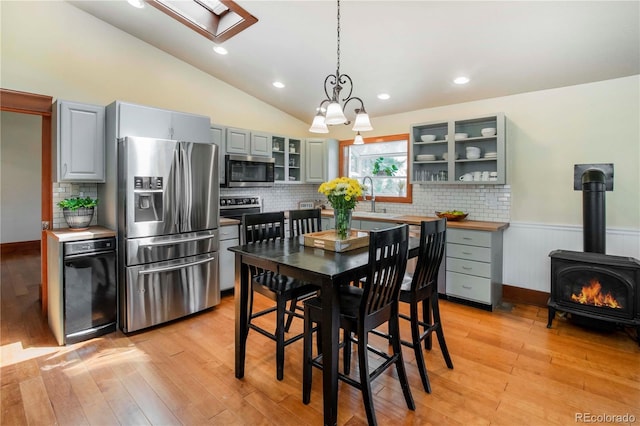 4805 S Blue Spruce Rd, Evergreen, CO 80439 - dining room with a wood stove, vaulted ceiling, light wood finished floors, a wainscoted wall, and recessed lighting