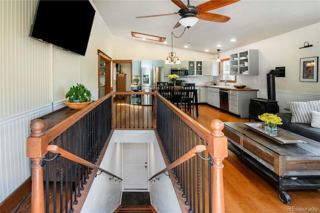 4805 S Blue Spruce Rd, Evergreen, CO 80439 - stairway with vaulted ceiling, a wood stove, a ceiling fan, and wood finished floors