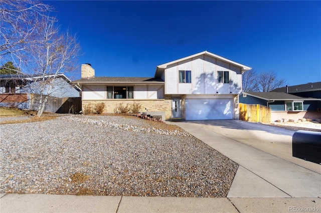 tri-level home with concrete driveway, fence, a chimney, and an attached garage