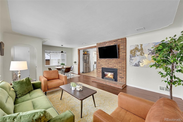 living room featuring a brick fireplace and light hardwood / wood-style floors