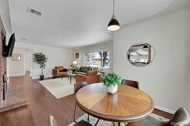 dining area featuring a brick fireplace and dark hardwood / wood-style flooring