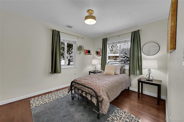 bedroom with dark hardwood / wood-style floors and multiple windows