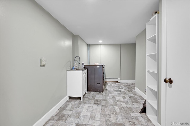 clothes washing area featuring cabinets, baseboard heating, and sink