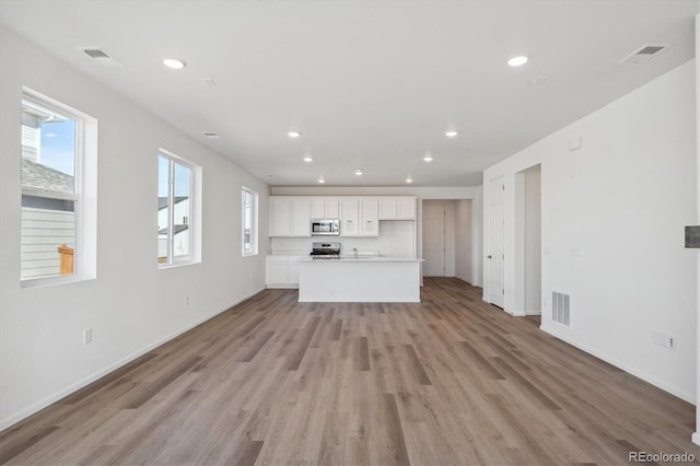 unfurnished living room featuring sink and light hardwood / wood-style floors