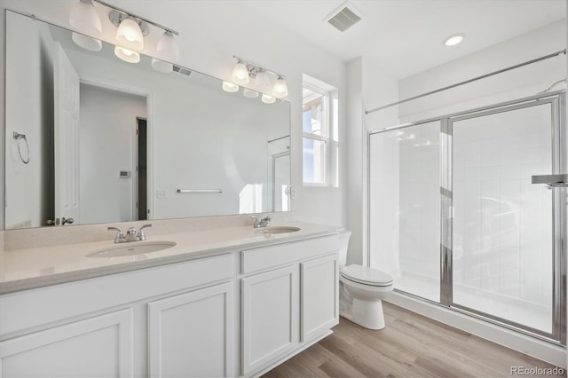 bathroom featuring vanity, hardwood / wood-style flooring, toilet, and a shower with door