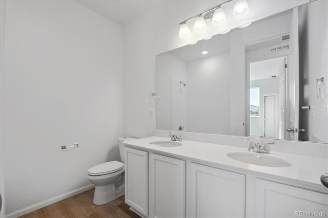 bathroom with hardwood / wood-style floors, vanity, toilet, and walk in shower