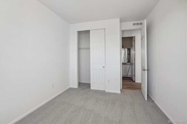 unfurnished bedroom with light colored carpet and a closet