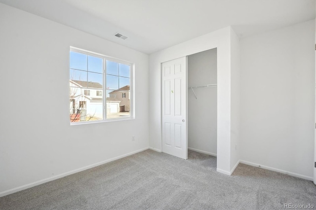 unfurnished bedroom with light colored carpet and a closet