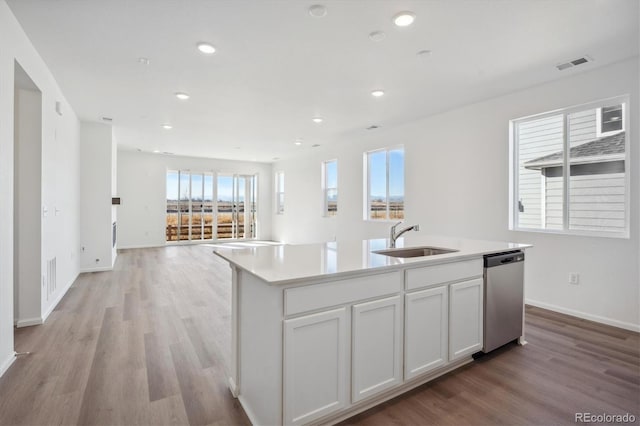 kitchen with sink, light hardwood / wood-style flooring, stainless steel dishwasher, a center island with sink, and white cabinets