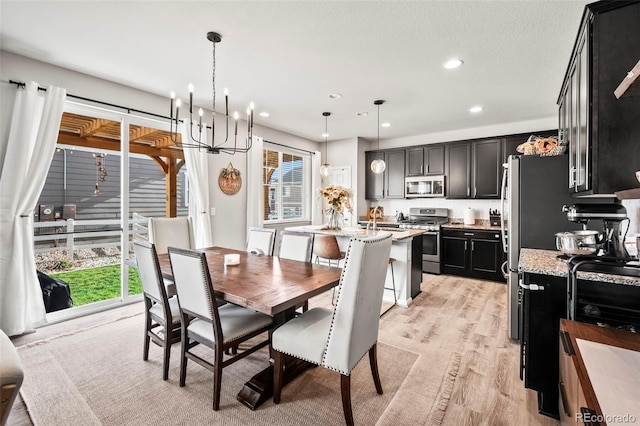 dining space featuring light hardwood / wood-style floors, an inviting chandelier, a healthy amount of sunlight, and sink