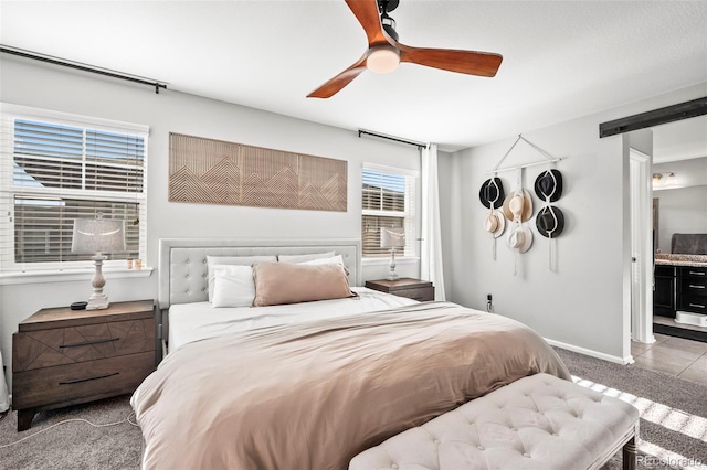 carpeted bedroom featuring a barn door, ceiling fan, and ensuite bathroom