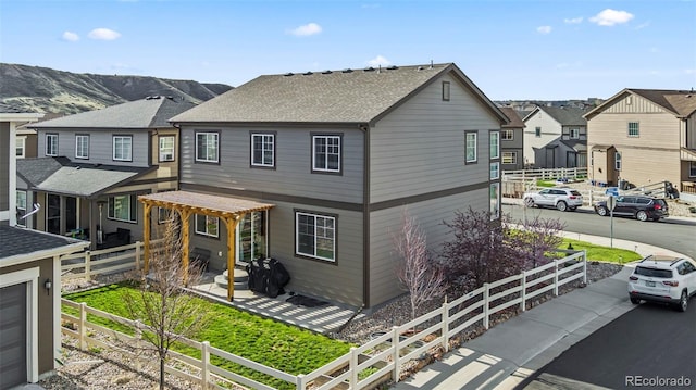 view of property with fence, a residential view, and a shingled roof