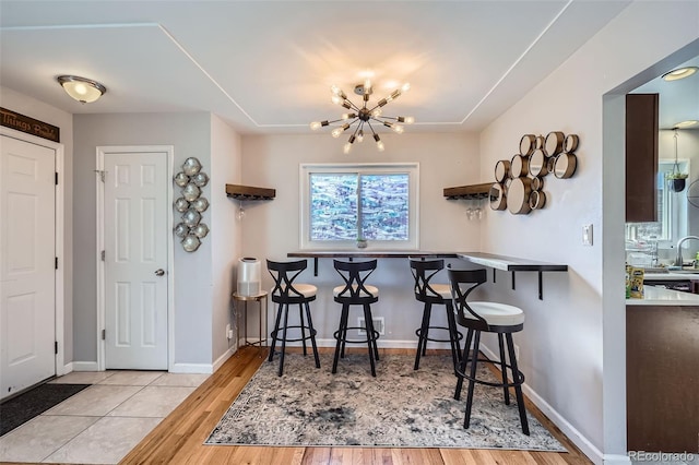 kitchen with a chandelier, a kitchen bar, and light hardwood / wood-style flooring