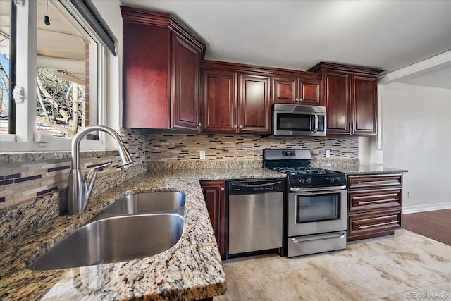 kitchen with backsplash, sink, stainless steel appliances, and stone counters