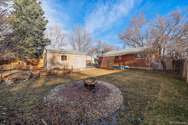 rear view of property with a lawn, an outbuilding, and an outdoor fire pit