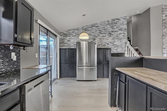 kitchen featuring tasteful backsplash, vaulted ceiling, decorative light fixtures, and appliances with stainless steel finishes