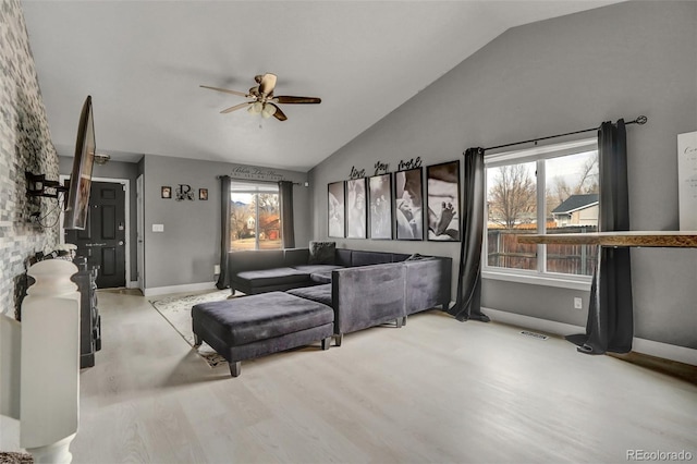 living room with ceiling fan, plenty of natural light, high vaulted ceiling, and light hardwood / wood-style floors