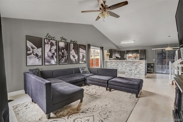 living room with ceiling fan, vaulted ceiling, and light hardwood / wood-style flooring