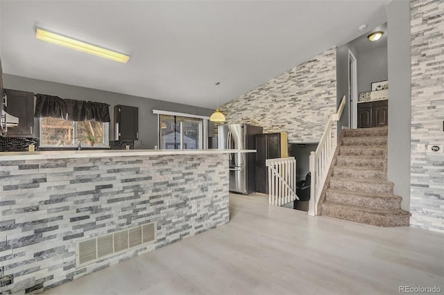 kitchen with stainless steel fridge, light hardwood / wood-style floors, hanging light fixtures, and lofted ceiling