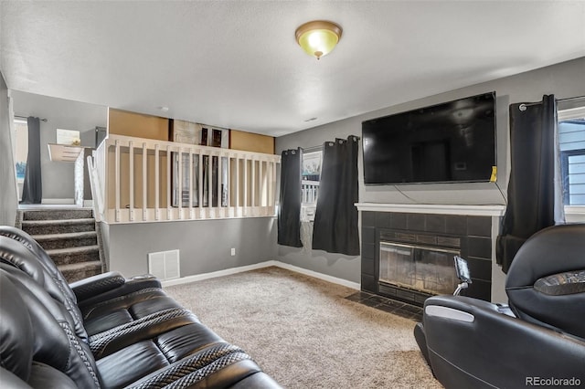 living room with carpet, a textured ceiling, a wealth of natural light, and a tiled fireplace