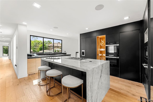 220 Glencoe St, Denver, CO 80220 - kitchen featuring dark cabinets, modern cabinets, a kitchen island, light wood finished floors, and recessed lighting
