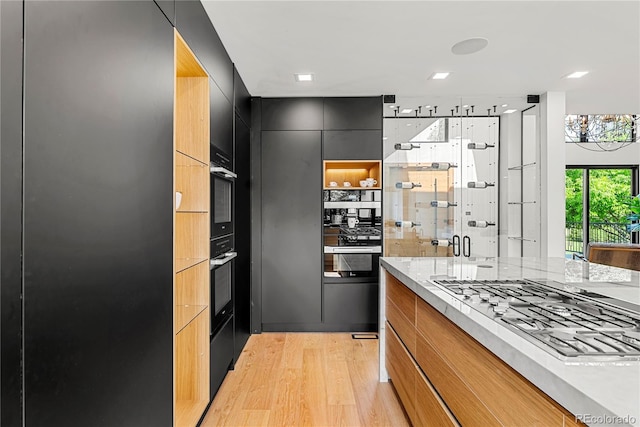 220 Glencoe St, Denver, CO 80220 - kitchen with modern cabinets, light wood-type flooring, stainless steel gas stovetop, and dark cabinets