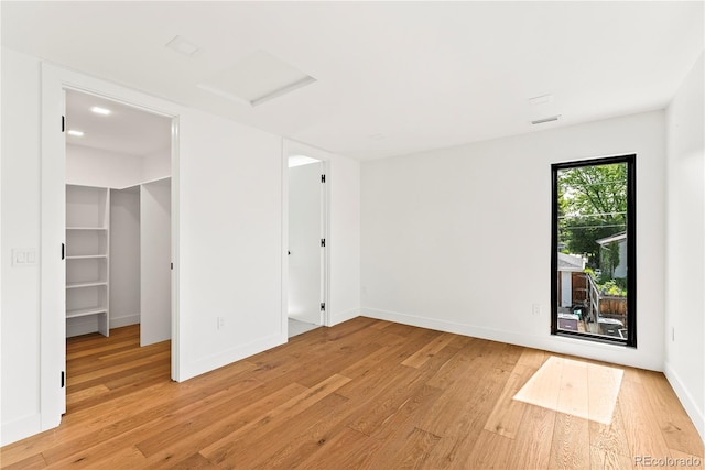 220 Glencoe St, Denver, CO 80220 - unfurnished bedroom featuring light wood-type flooring, a spacious closet, attic access, and baseboards