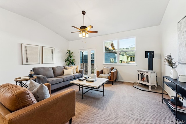 living room featuring baseboards, a wood stove, ceiling fan, vaulted ceiling, and light carpet