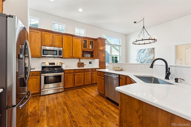 kitchen with brown cabinets, a sink, dark wood finished floors, stainless steel appliances, and light countertops