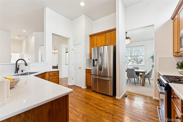 kitchen featuring dark wood-type flooring, light countertops, brown cabinetry, stainless steel appliances, and a sink